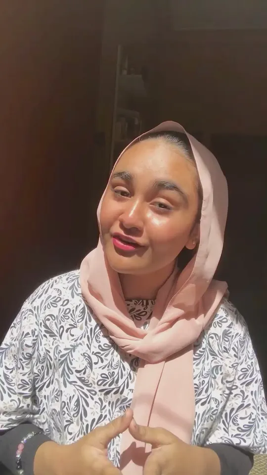 A creator in a pink scarf talking to camera about her skincare